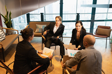 businesswoman and businessman in black suit working about financial graph with colleague men in workplace with window background. colleague man and woman working in modern office