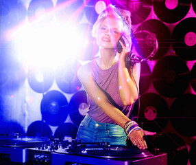 Fototapeta na wymiar Portrait, woman dj and headphones for retro, nightclub and party with neon lights and lens flare. Happy gen z person, listen and mixing tracks and vinyl at rave or techno music event in Berlin disco