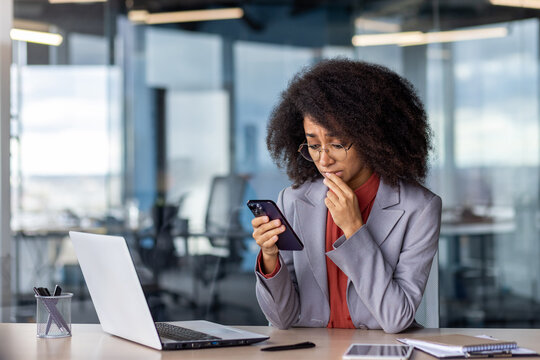 Sad woman with bushy hairstyle touching mouth with fingers with pitiful expression while using mobile telephone. Worried female looking at gadget screen and reading harsh message from director
