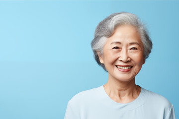 Portrait of older Chinese woman smiling isolated on solid blue background