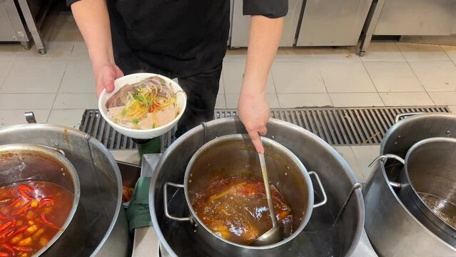 pour fa soup vietnam. Hands pouring broth into bowls of pho