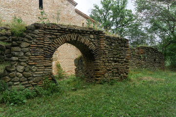 Ancient church in the forest. Bricks and stone wall. Partially destroyed arched extension at the...