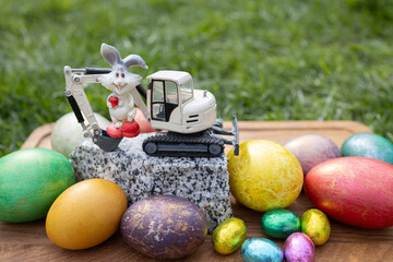 model of a toy excavator on a piece of granite, a souvenir rabbit, colorful eggs. Easter spring...