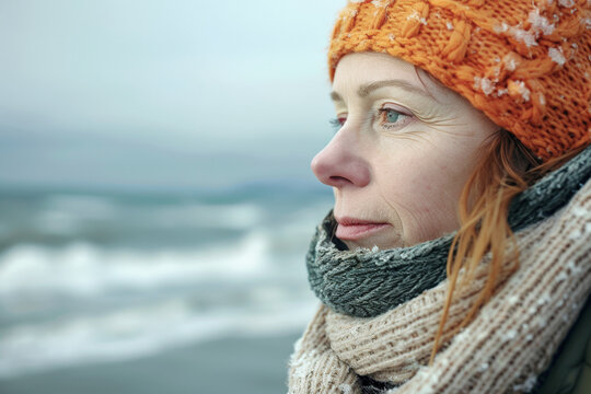 Contemplative Cold: A Woman in Scarf and Hat Stands by the Sea