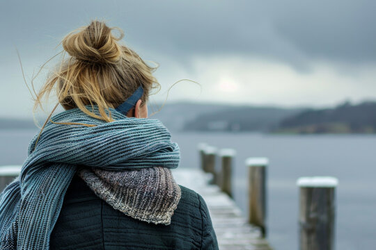 Gazing at the Sea: Woman in Oversized Scarf Standing on Pier