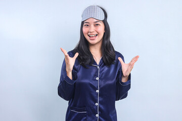 Excited Young Asian Woman Wearing Pajama and Eye Mask Over Gray Background