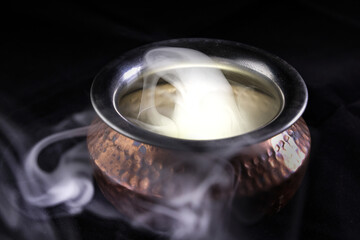 Brass copper metal style pot cauldron smoke vape fog lit inside rising flowing moving rotate on black background - 742451267