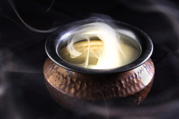 Brass copper metal style pot cauldron smoke vape fog lit inside rising flowing moving rotate on black background - 742451628