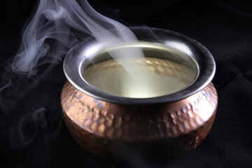 Brass copper metal style pot cauldron smoke vape fog lit inside rising flowing moving rotate on black background - 742451636