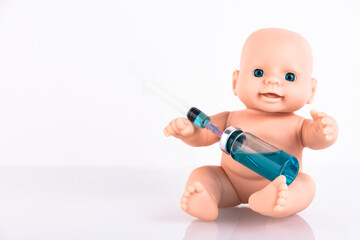 The baby doll is holding a medical syringe and an ampoule with a vaccine. Vaccine for newborns Concept. Copy space.