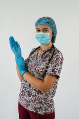 female young nurse in mask putting on blue sterilized surgical gloves isolated on white