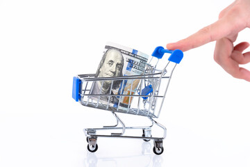 A hand in the form of a walking man rolls up a shopping cart with a roll of one hundred dollar bills. Copy space. © PRO Balance