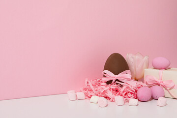 Chocolate eggs with gifts on a pink background