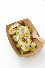 a paper container filled with cheese-topped tater tots and there was a fork