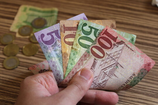 man counting saudi arabian  money with his hand. saudi arabian rial banknotes. The paper currency of saudi arabia. For tax and hike news. raise, tax, minimum wage