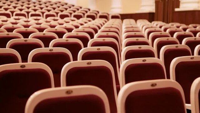 Red soft chairs of an empty auditorium, concert hall. Close-up.
