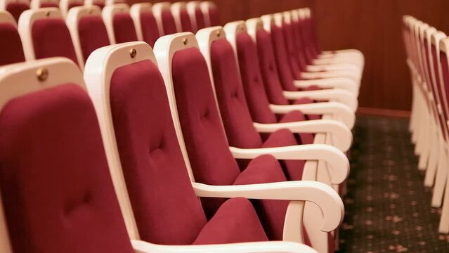 Red soft chairs of an empty auditorium, concert hall. Selective focus.