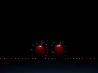 Two plum tomatoes surrounded by red pins against a black background