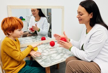 Sensory game with massage ball. Cute male child playing in sensory game with professional child therapist in rehab center