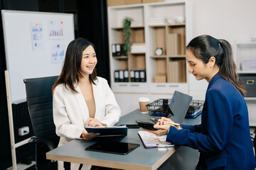Two business workers talking on the smartphone and using laptop at the office..