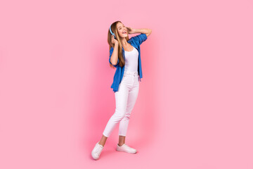 Fototapeta na wymiar Full length photo of excited cheerful lady dressed blue shirt enjoying songs earphones singing isolated pink color background