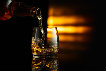 Pouring whiskey from a bottle into a glass.