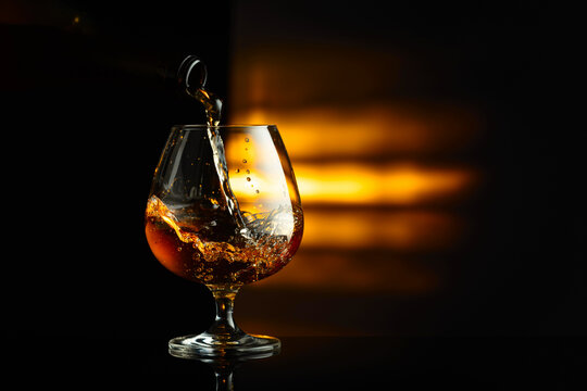 Pouring brandy from a bottle into a snifter.
