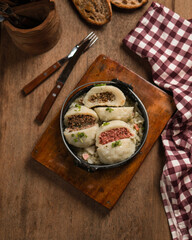 four fluffy steamed buns in a bamboo steamer basket,a golden brown crust and are dusted with flour.
