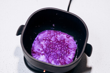 Purple granules are heated in a black wax melter. Eyebrow tools