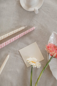 Overhead view of assorted candles, blank paper card and gerbera flowers on a table