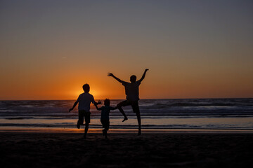 Happy children, boys, playing on the beach on sunset, kid cover in sand, smiling, laughing