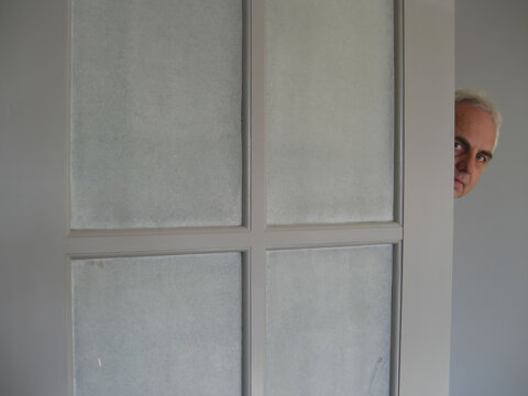 Portrait of a man's face peeking round an open door