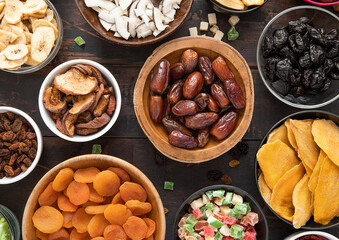Mixed healthy dried sweet berries and fruits snack in various bowl plates on wooden background.Top view.