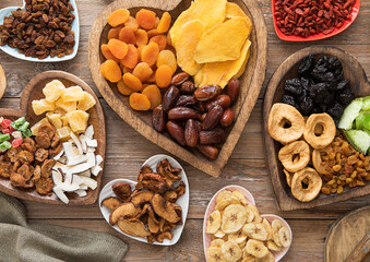 Healthy sweet dried fruits and berries in wooden heart shaped plates on wooden background.Top view.