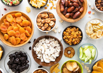 Assorted organic dried sweet fruits and berries in various bowl plates on light kitchen background.Top view.