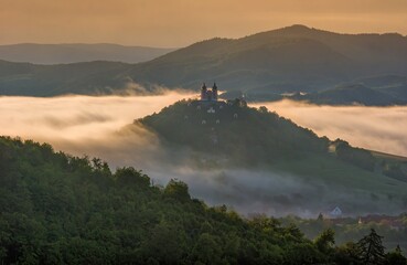 Summer morning at sunrise with fog and historic chapel on the hill, hiking in the mountains.. Calvary over clouds in Banska Stiavnica, Slovakia