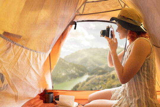 Woman in tent in morning drinking coffee taking pictures with hat