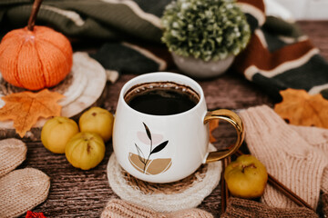 Fototapeta na wymiar Big mug of hot dark coffee, sweet candies, autumn leaves and handmade woolen clothes on wooden background, vintage scene