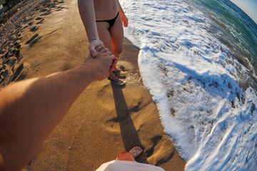 Romantic young couple holding hands on the beach, enjoying romance and love by the sea.