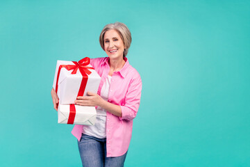Photo of pensioner business woman in pink shirt holding two gift boxes for colleagues in christmas isolated on blue color background