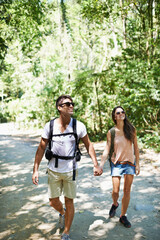 Walking, hiking and couple holding hands in nature for adventure, freedom and backpacking outdoors. Travel, bonding and man and woman on trail for holiday, vacation or trekking for wellness in forest