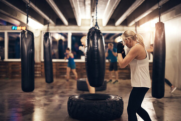 Fit woman working out with a punching bag in a boxing gym class