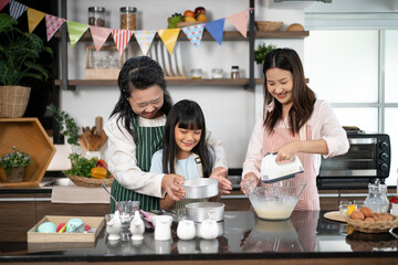 Asian female baker pastry chef mother and old senior grandmother helping teaching little girl daughter niece standing smiling holding using sieve sifting flour powder into glass bowl preparing dough - 742550095