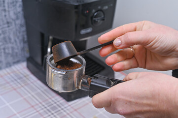 women's hands pour coffee into the portafilter of the coffee machine. close-up