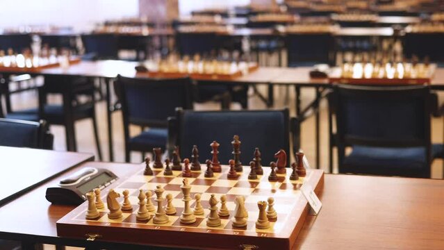 Chess tournament, kids and adults participate in chess match game outdoors in indoor hall, players of all ages play, competition in chess school club with chessboards on a table