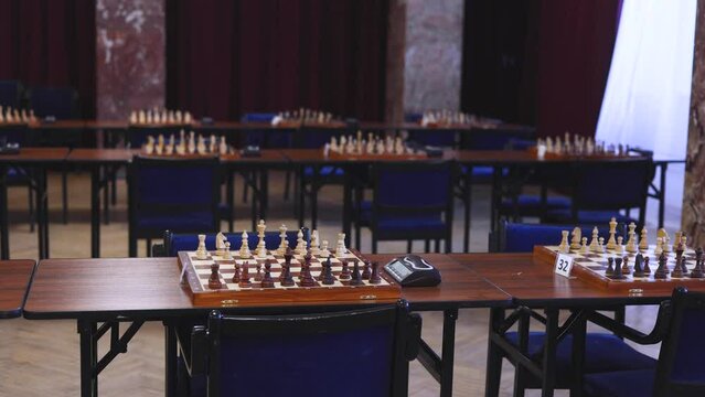Chess tournament, kids and adults participate in chess match game outdoors in indoor hall, players of all ages play, competition in chess school club with chessboards on a table