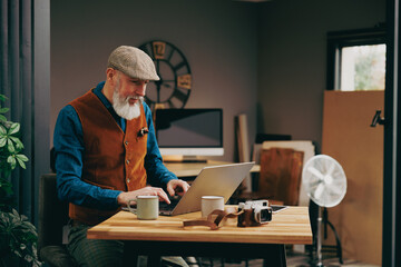 Portrait d'un photographe homme barbu chic hipster élégant et stylé qui porte un appareil photo vintage argentique dans un atelier créatif