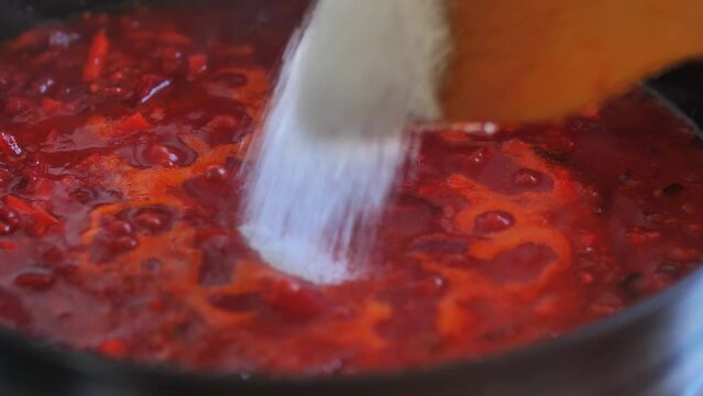 Chef's hand throws sugar into a stewpan and mixes vegetables in tomato sauce. healthy food, vegetarian cuisine. Tasty taste, homemade dish. Slow motion