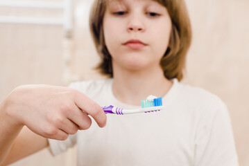 Teenage boy in casual wear brushing teeth in bathroom during morning hygiene routine, Morning ritual: Boy applies toothpaste, embracing dental care in the bathroom