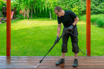 man cleaning terrace with a power washer - high water pressure cleaner on wooden terrace surface - 742566245